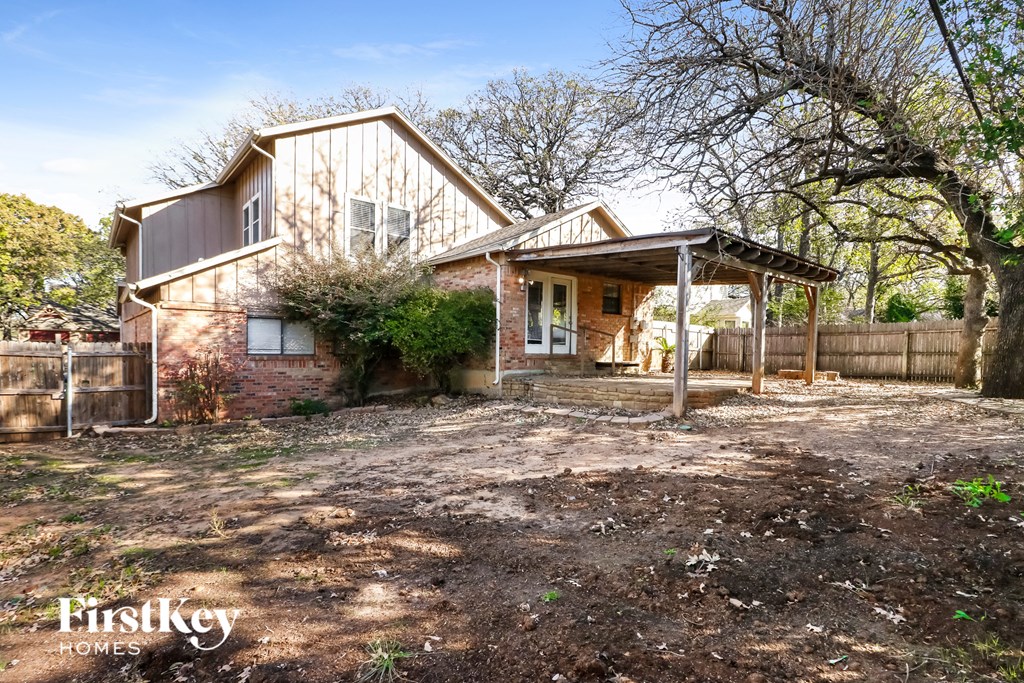 a small brick house with a porch and a fence