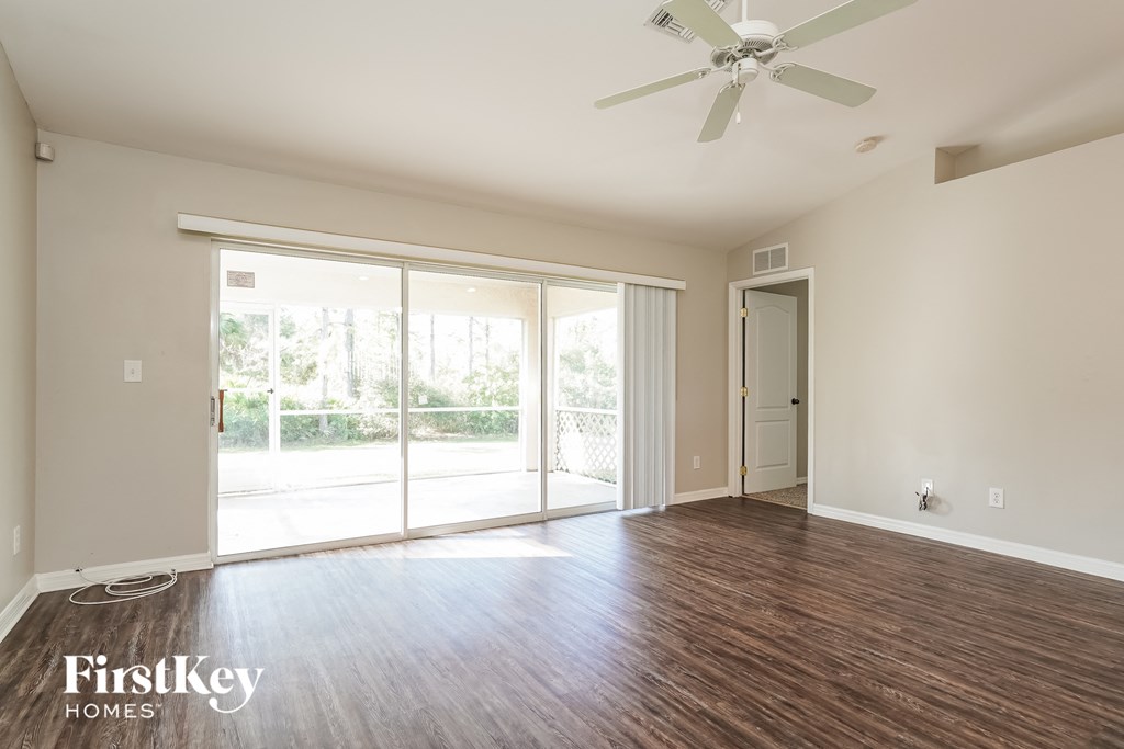 an empty living room with wood flooring and a ceiling fan
