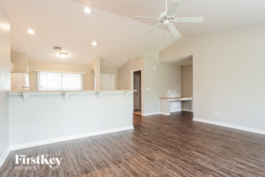 a living room with a kitchen and a ceiling fan