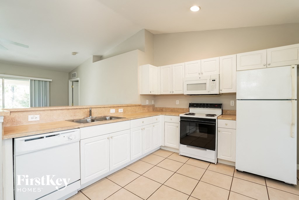 a kitchen with white cabinets and appliances and tiled floors