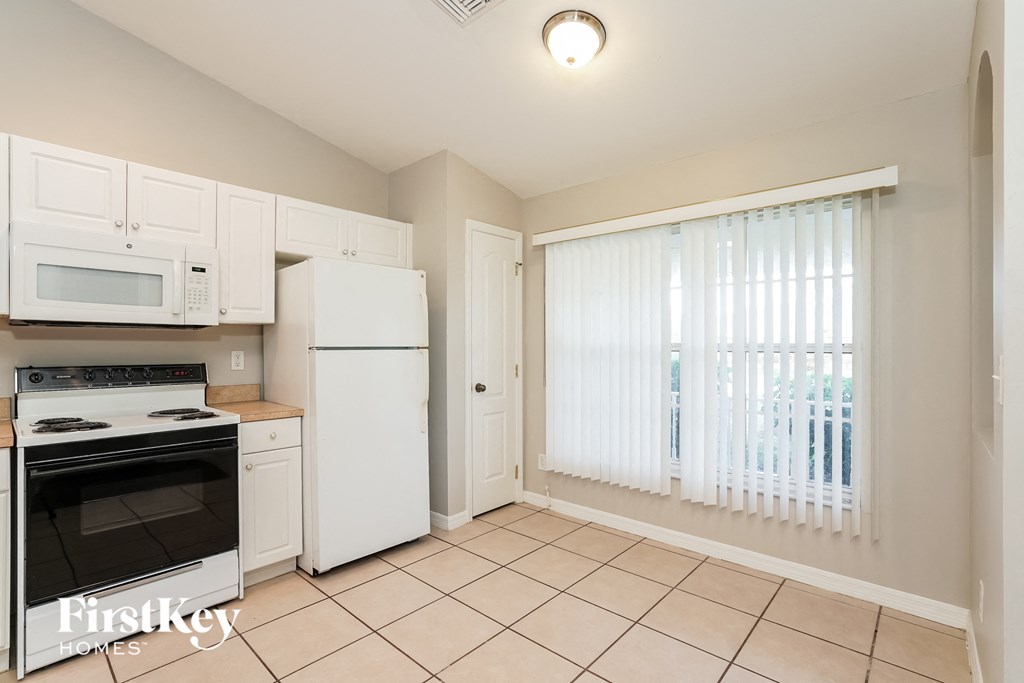 a kitchen with white appliances and a large window