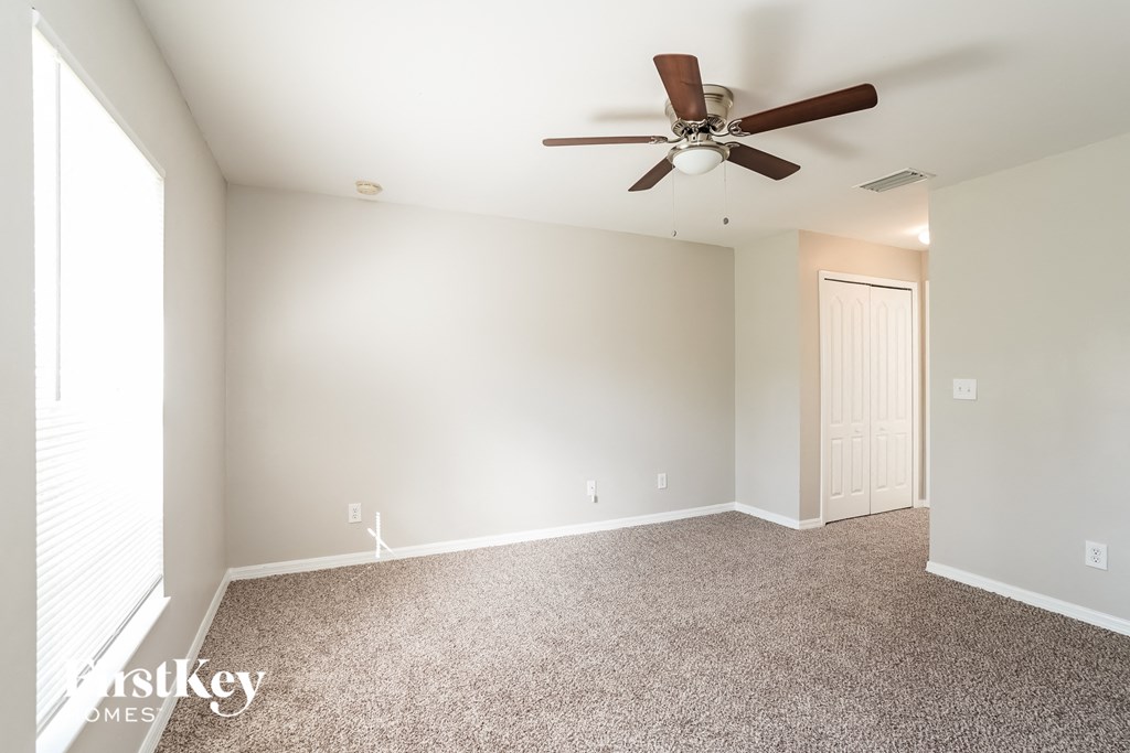 an empty living room with a ceiling fan and carpet