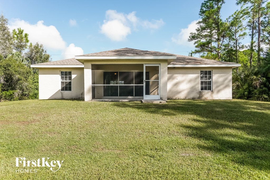 a small white house with a lawn and trees