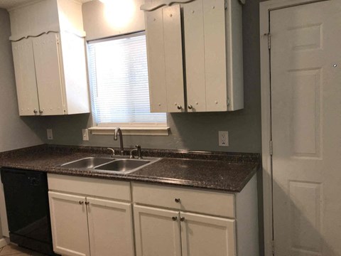 A kitchen with white cabinets and a granite countertop.