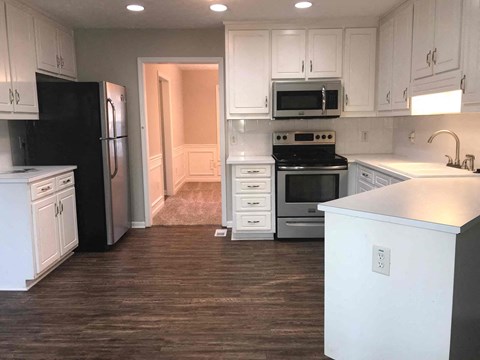 A kitchen with white cabinets and black appliances.
