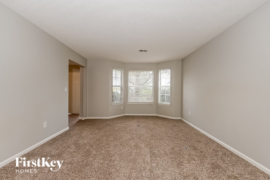 an empty living room with carpet and a window