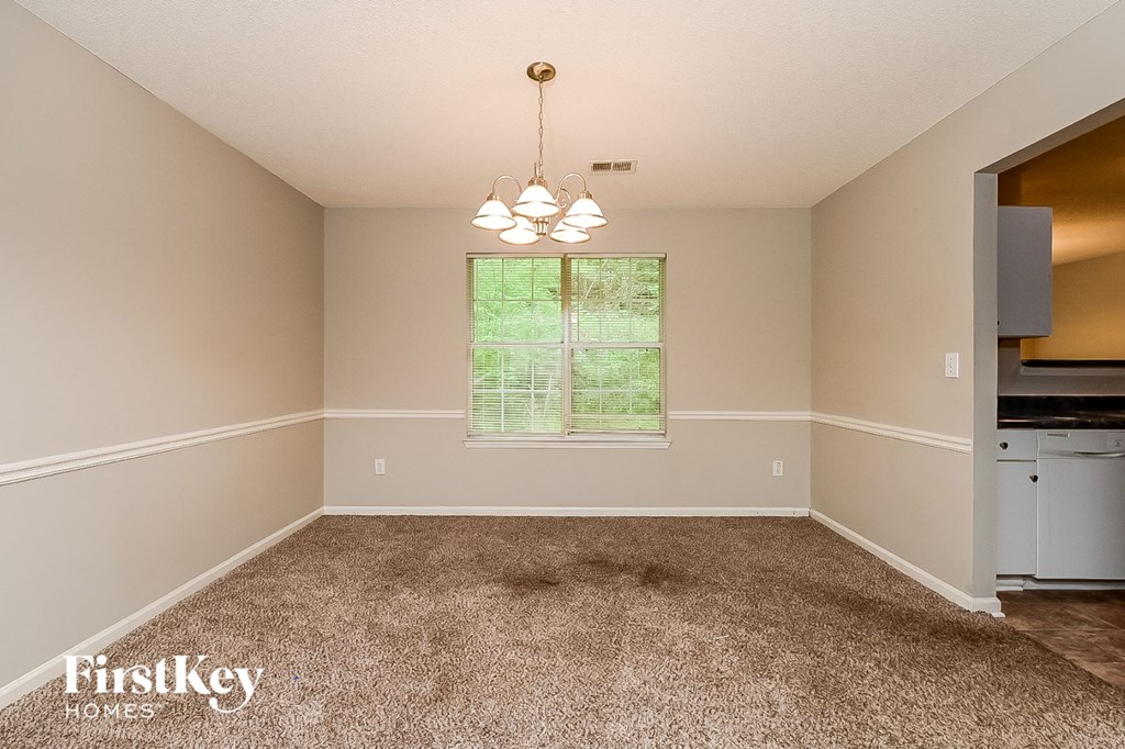 an empty dining room with carpet and a window