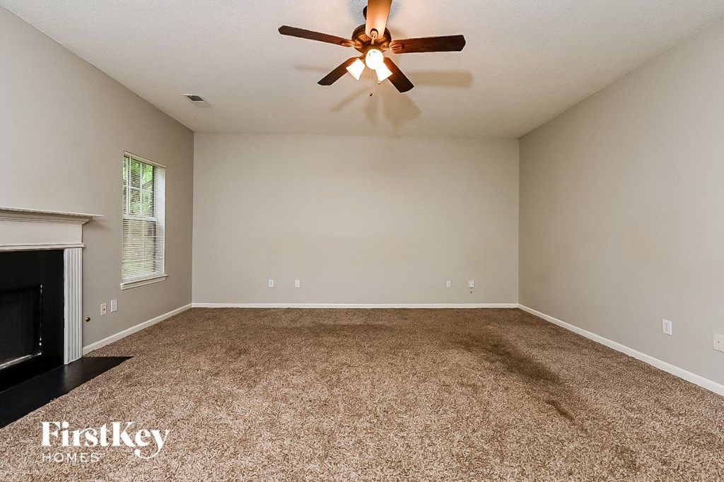 the spacious living room with fireplace and ceiling fan