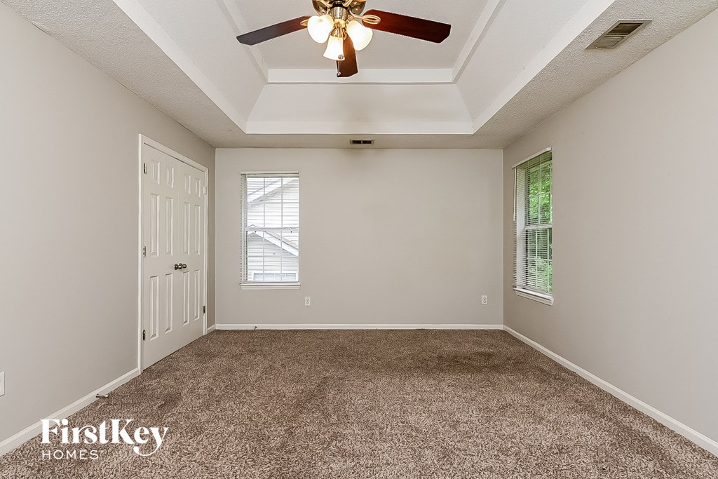 the master bedroom has a ceiling fan and a carpeted floor