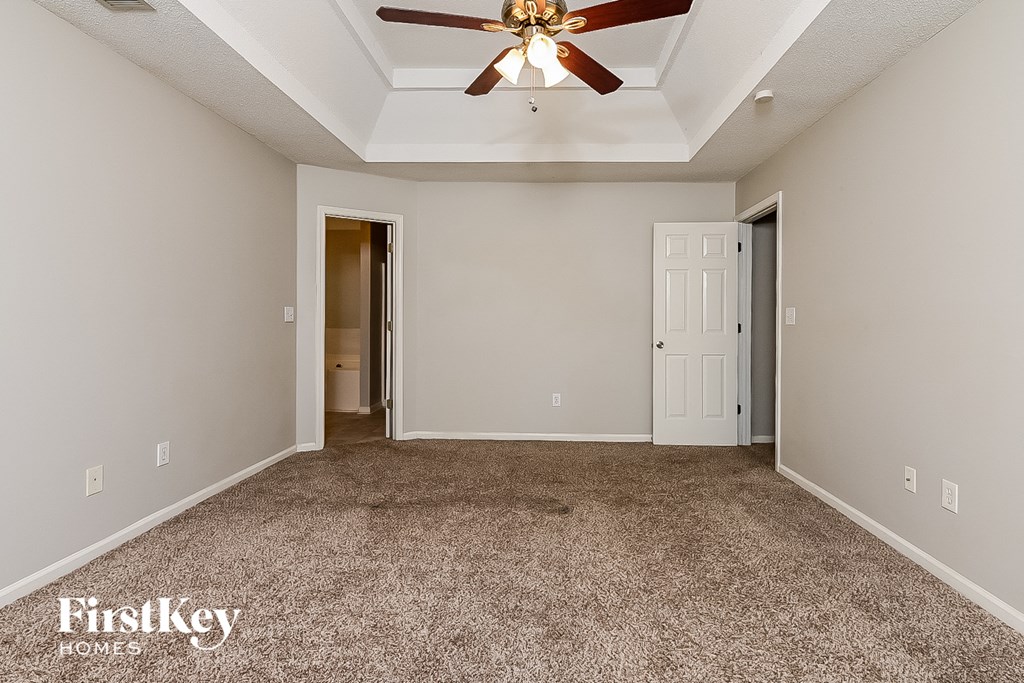 an empty living room with carpet and a ceiling fan