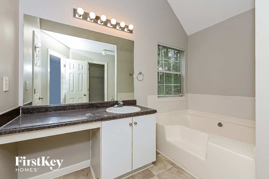 a bathroom with a sink and a tub and a mirror