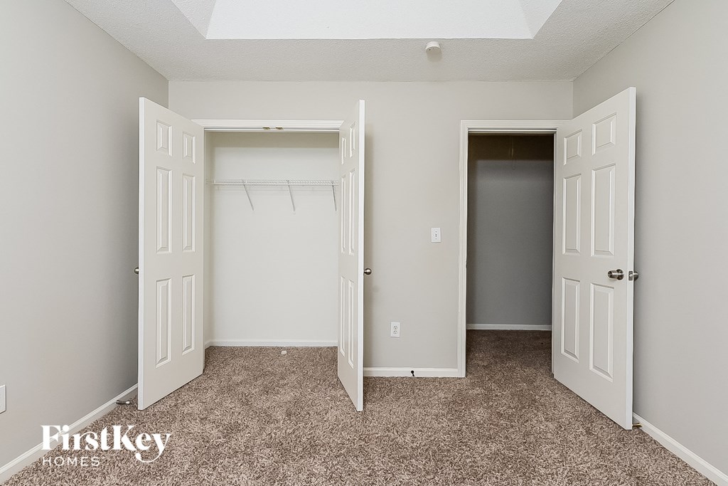 a bedroom with two closets and two doors and a carpeted floor