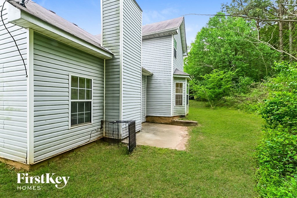 the back of a white house with a yard and a gate