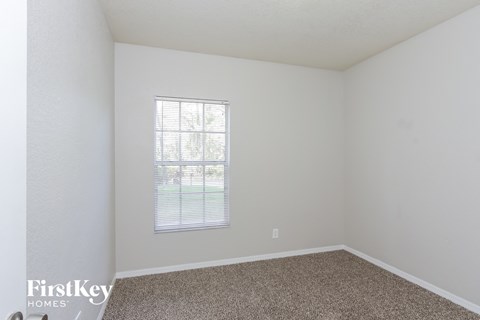 a bedroom with white walls and carpet and a window