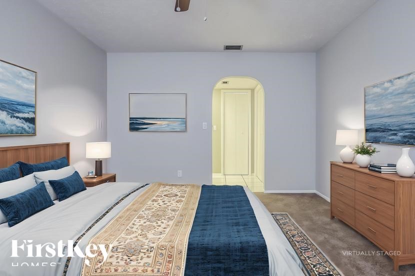 A bedroom with a bed, nightstand, and two paintings on the wall.