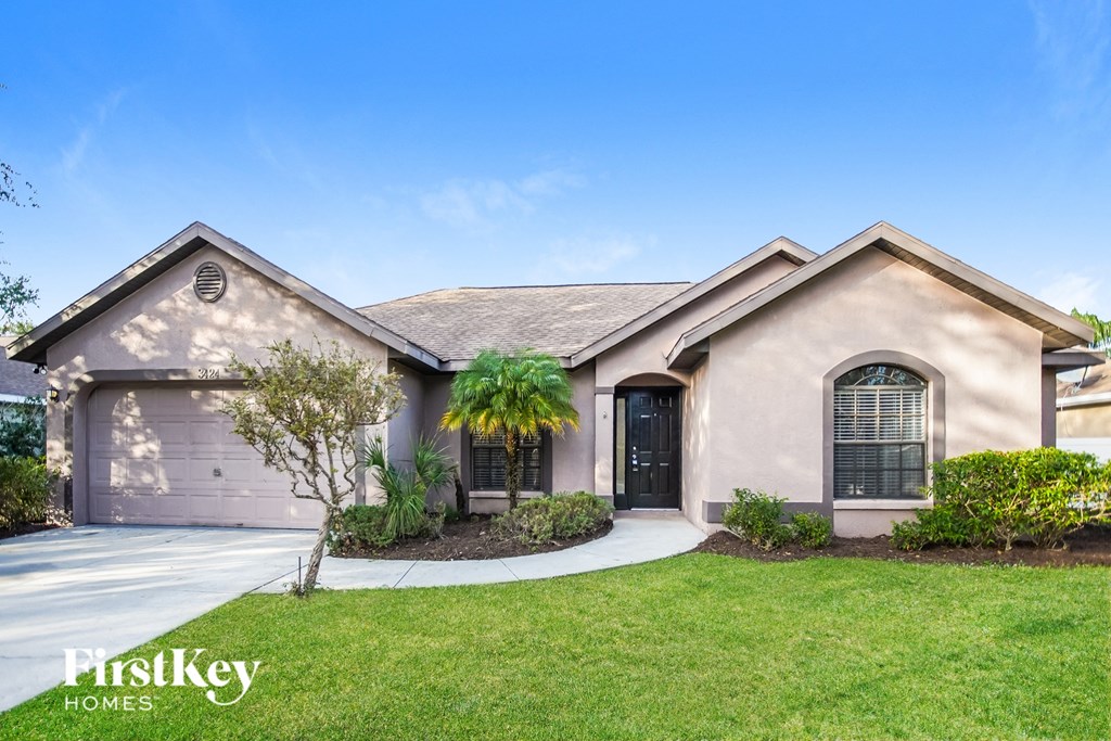a beige house with a garage door and a lawn