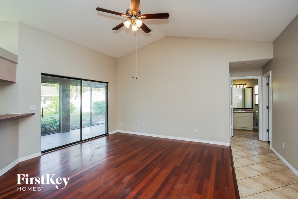 an empty living room with wood floors and a ceiling fan