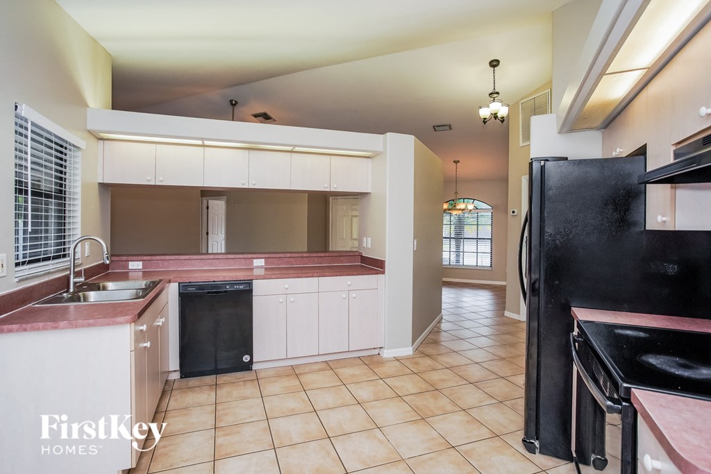 a kitchen with white cabinets and a black refrigerator