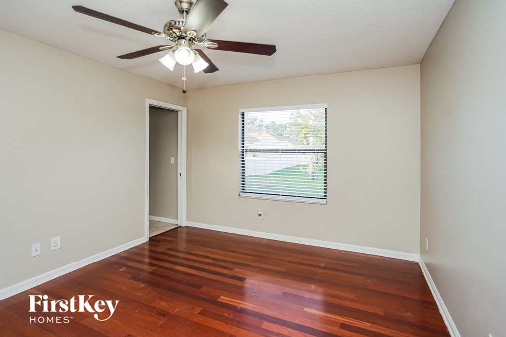 an empty living room with wood floors and a ceiling fan