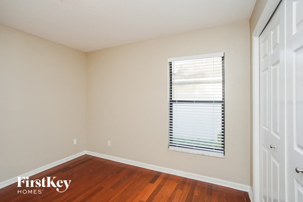 a bedroom with wood flooring and a window with blinds