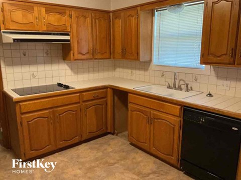 A kitchen with wooden cabinets and a black dishwasher.