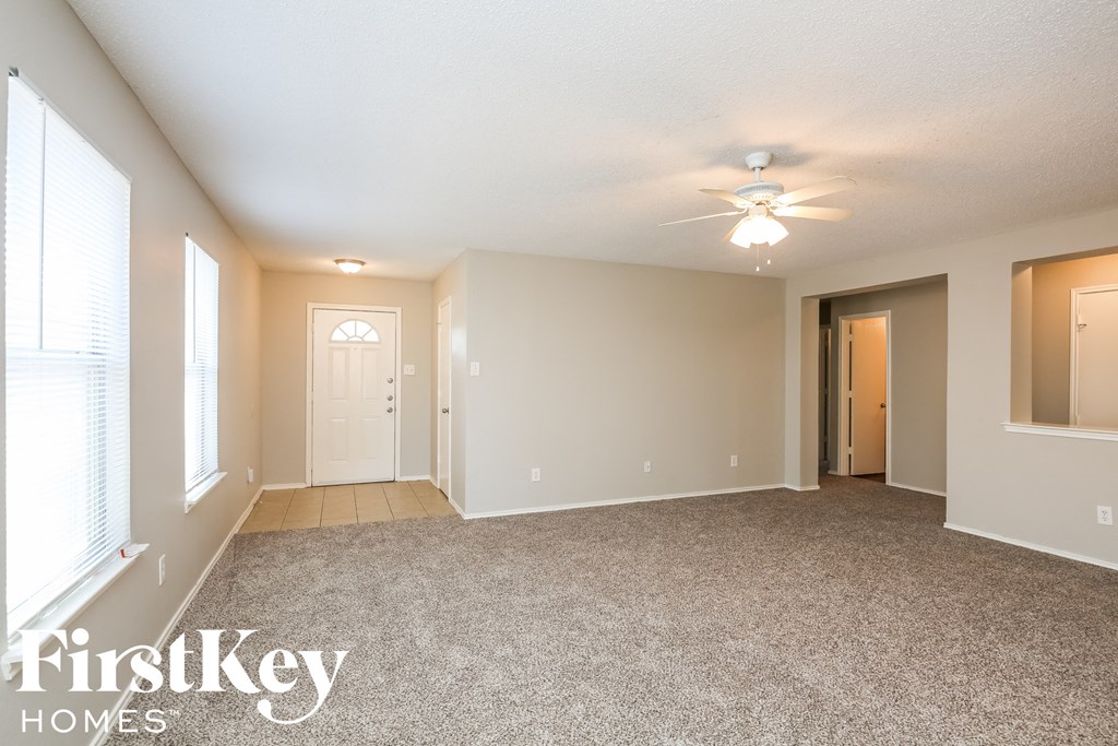 an empty living room with a ceiling fan and window