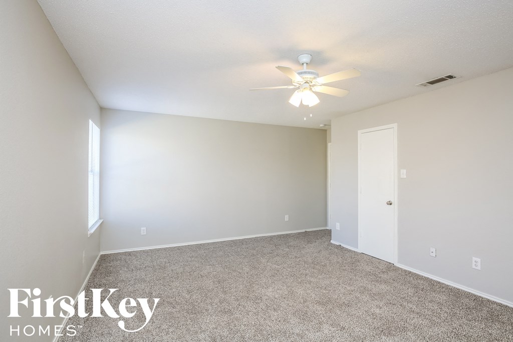 the spacious living room with carpeting and a ceiling fan