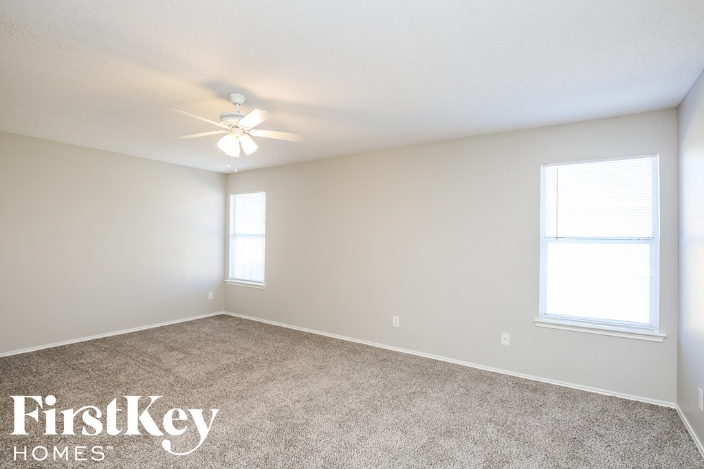 a bedroom with carpet and a ceiling fan and two windows