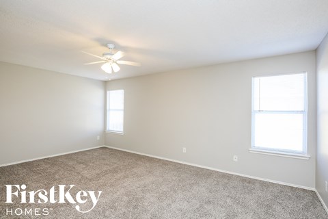 a bedroom with carpet and a ceiling fan and two windows