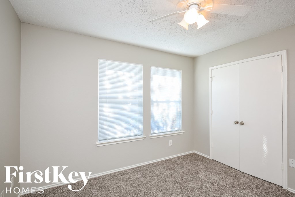 a bedroom with two windows and a ceiling fan