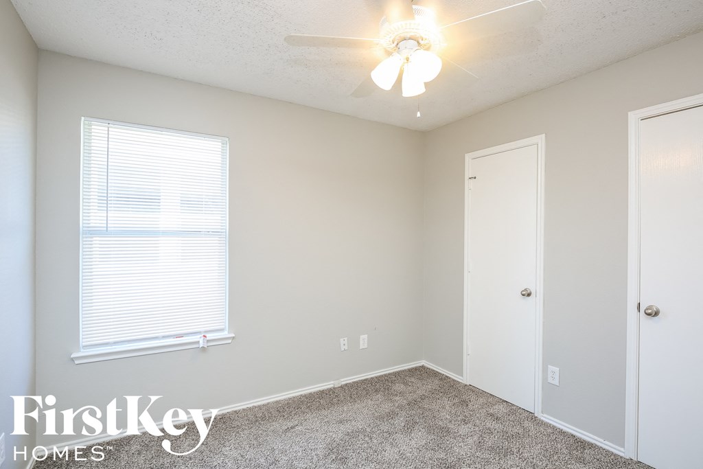 a bedroom with a ceiling fan and a door and a window