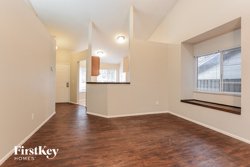 the living room and dining room with wood flooring and a large window