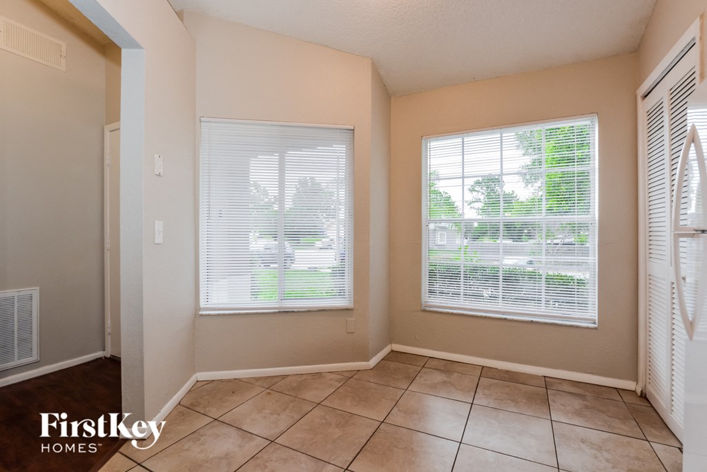 the living room of a home with two windows and a tiled floor