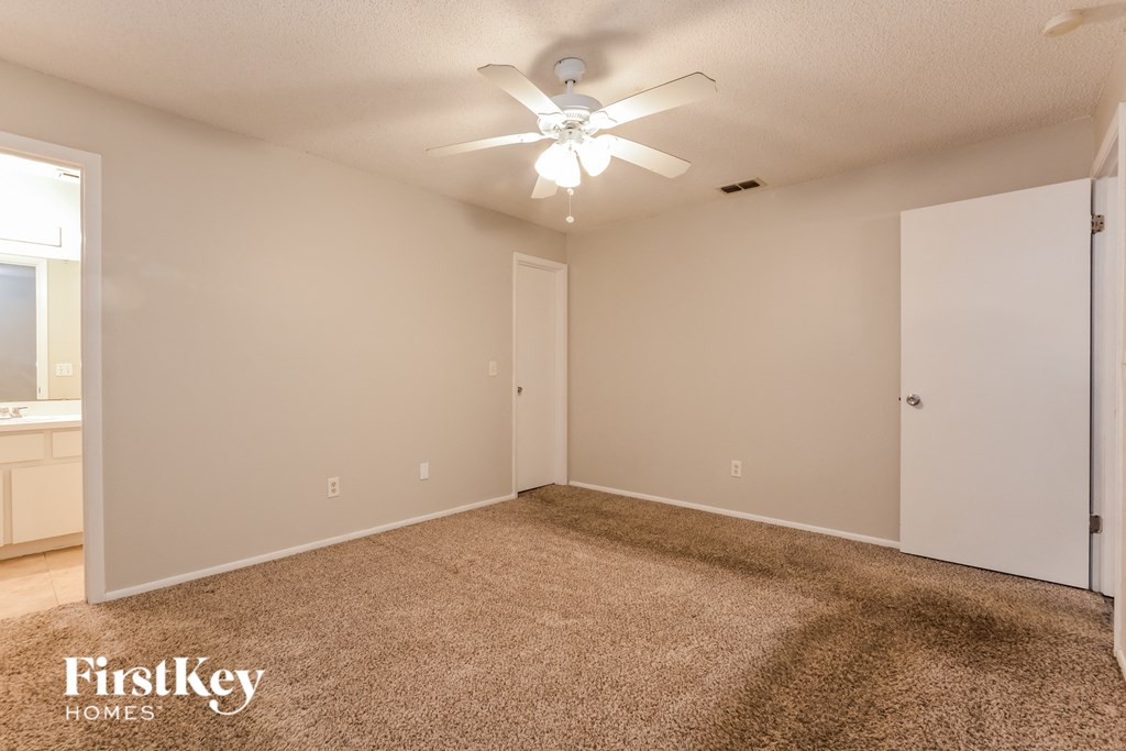 the spacious living room with carpeting and a ceiling fan