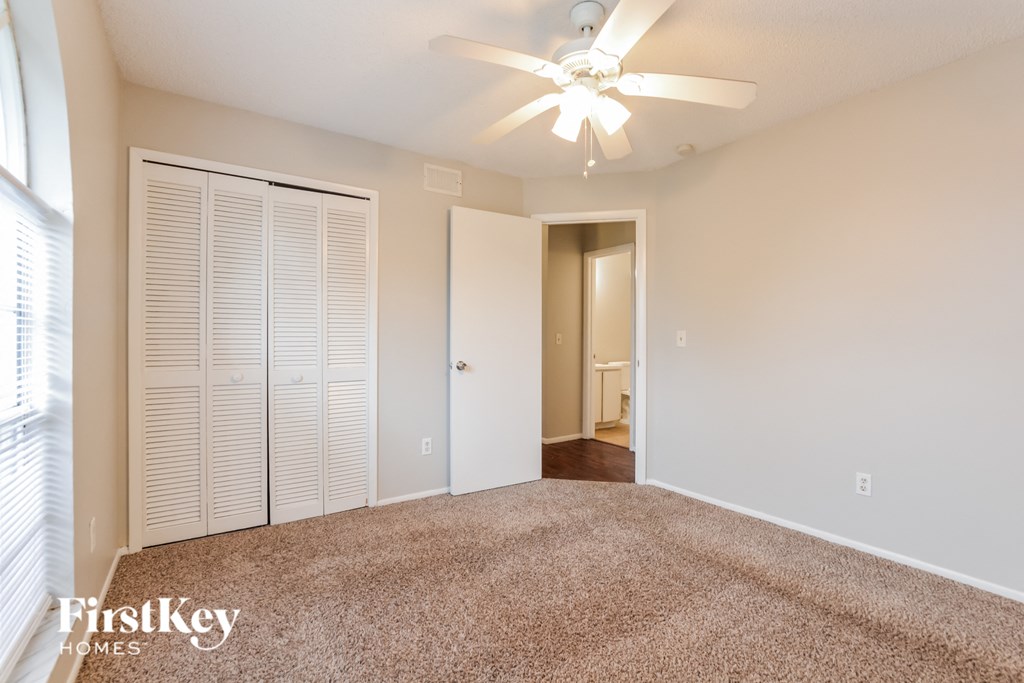 a spacious living room with carpet and a ceiling fan