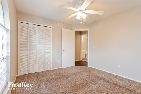 a spacious living room with carpet and a ceiling fan