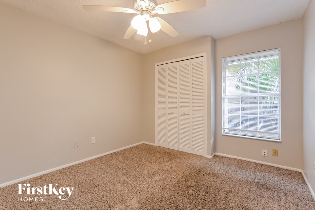 the spacious living room in this home has carpeting and a ceiling fan