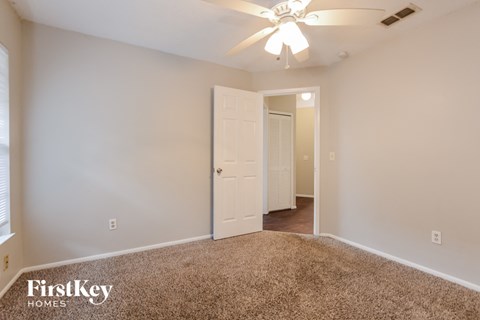 a bedroom with a white door and a ceiling fan