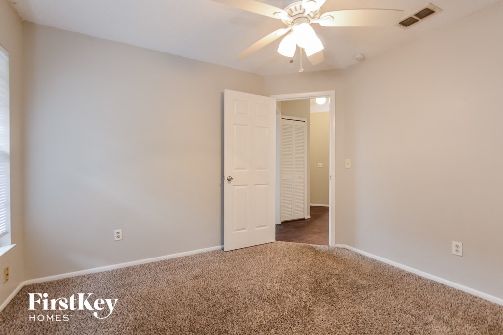 a bedroom with a white door and a ceiling fan