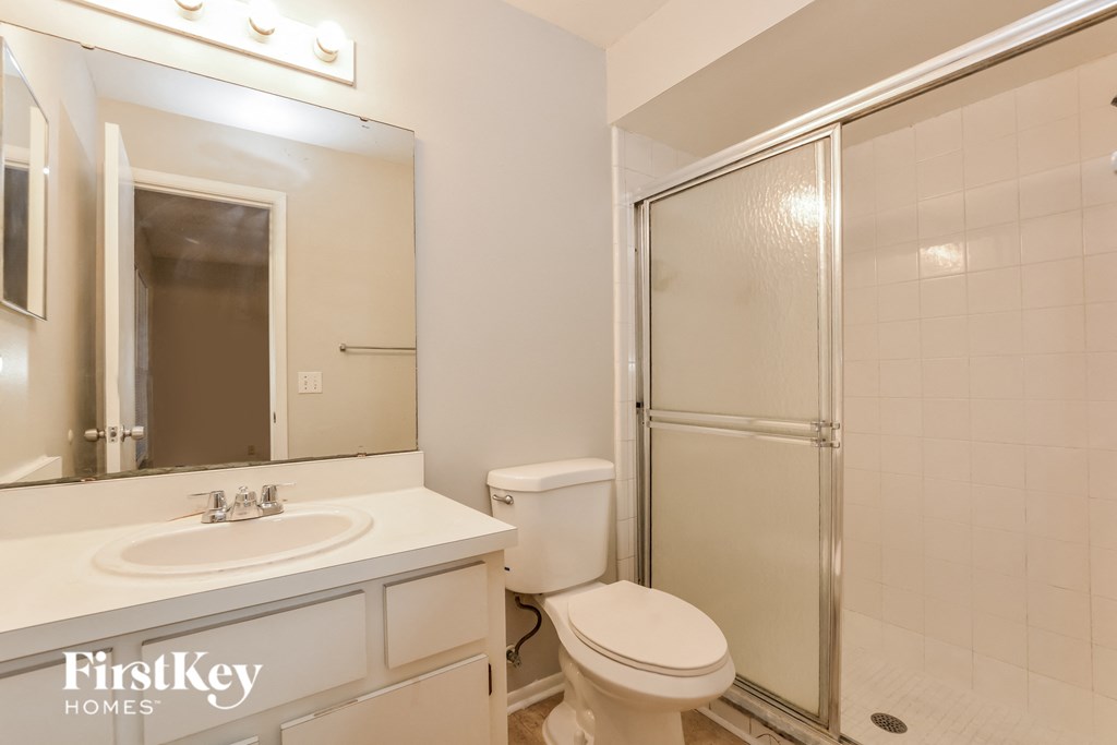 a white bathroom with a shower toilet and sink