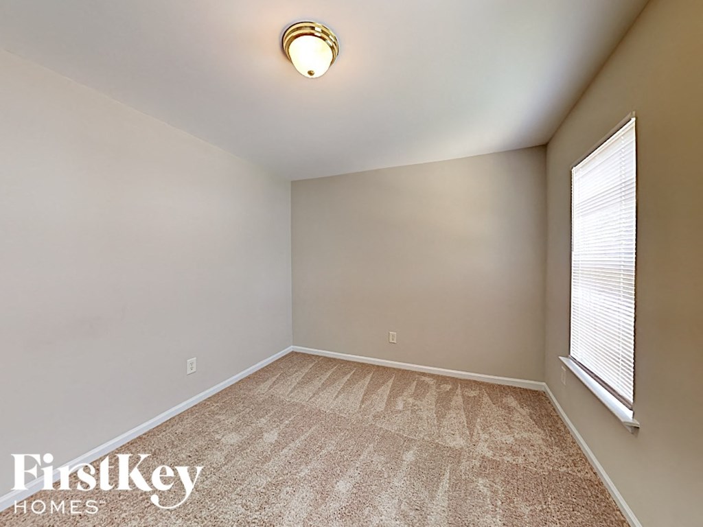 an empty room with carpet and two windows