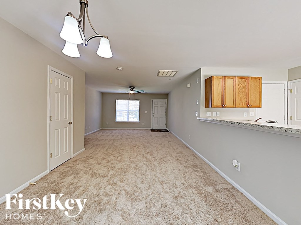 an empty kitchen and living room with carpeting and a white door