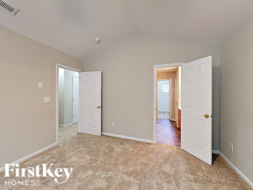 a bedroom with two closets and two doors and a carpeted floor