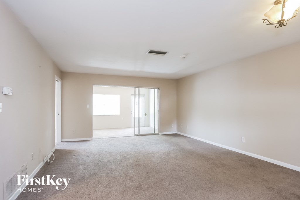 A spacious room with a carpeted floor and a sliding glass door.