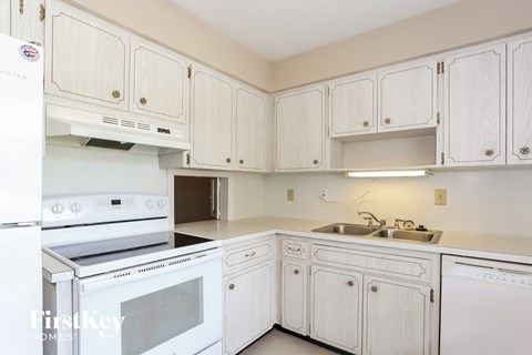 A white kitchen with a stove, oven, and cabinets.