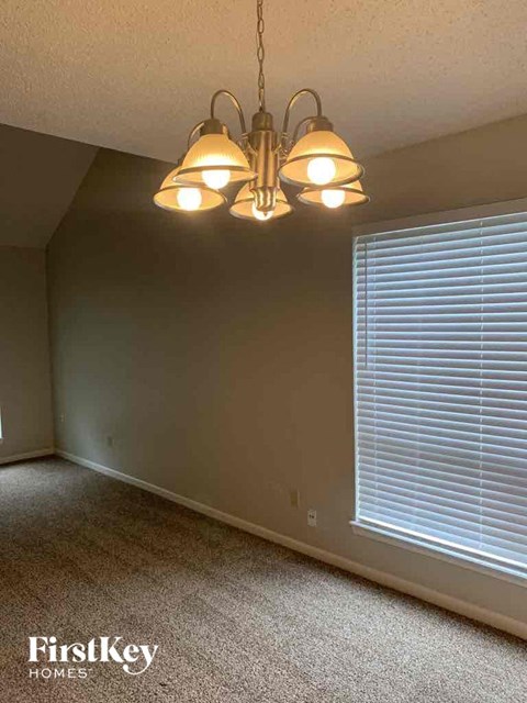 a bedroom with a chandelier and a large window with blinds