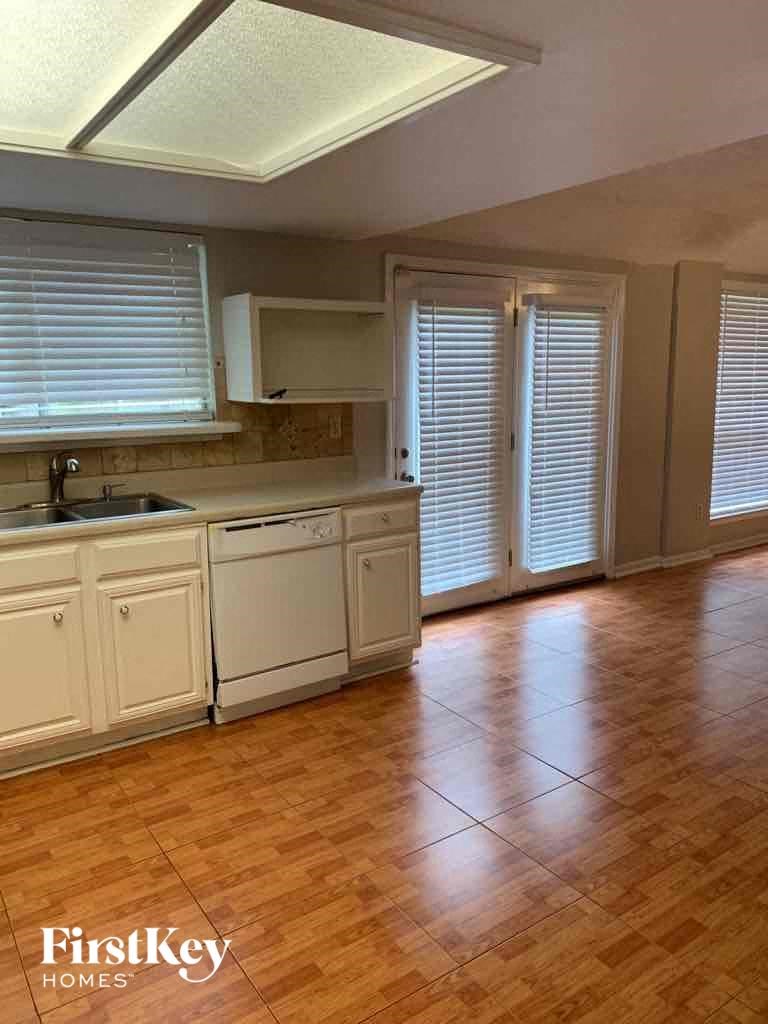 an empty kitchen with a wood floor and white cabinets