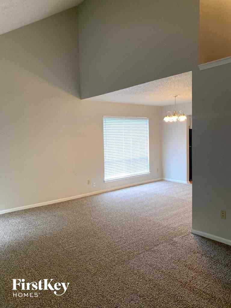 an empty living room with white carpet and a window