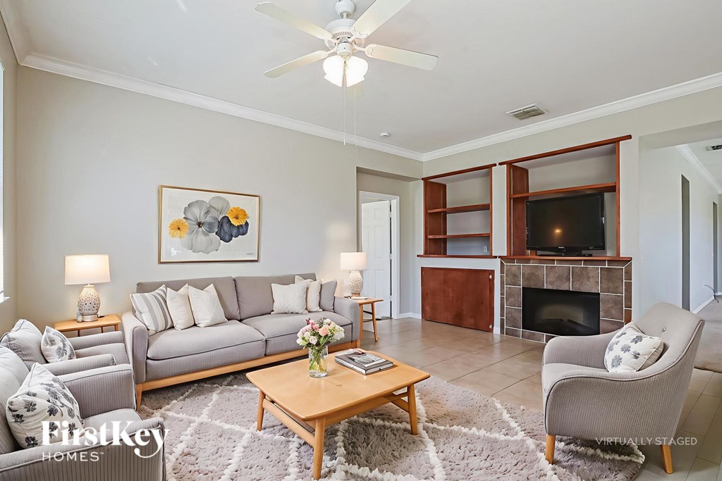 A living room with a grey couch, a coffee table, a fireplace, and a painting on the wall.