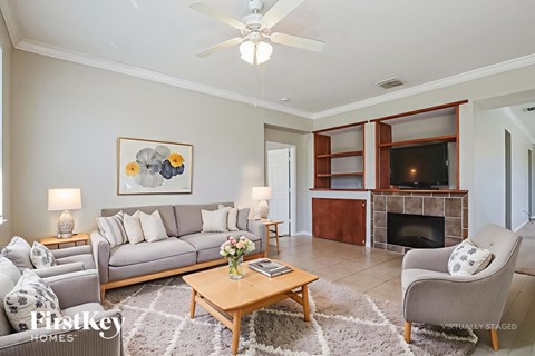 A living room with a grey couch, a coffee table, a fireplace, and a painting on the wall.